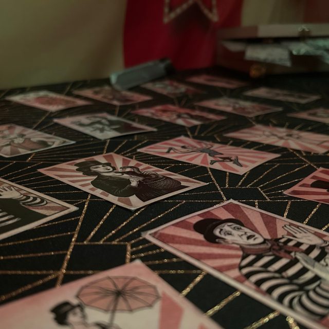 Table couverte de cartes à jouer illustrées de clowns rose et noir, salle Circus chez Prisme Escape Game