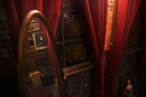 Miroir ovale, rideaux rouges et meubles anciens dans une pièce sombre, salle Dracula chez Hint Hunt à Paris