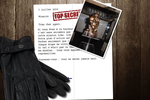 Lettre de mission secrète, gants noirs et statuette dans l'atelier d'Esc'ape