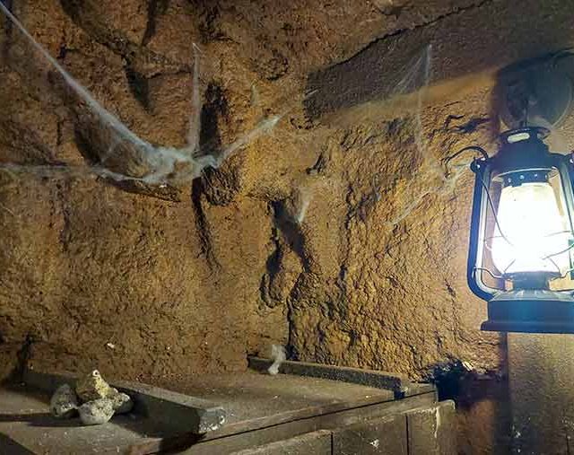 Paroi de roche aux toiles d'araignée et lanterne allumée, salle La ruée vers l'or chez Time Lapse à Soorts-Hossegor