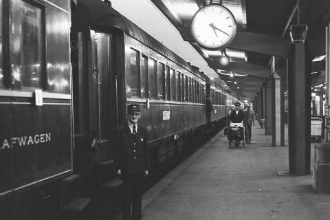 Quai de gare avec train, horloge, porteur en uniforme, voyageurs chez 221B Baker Street à Dijon