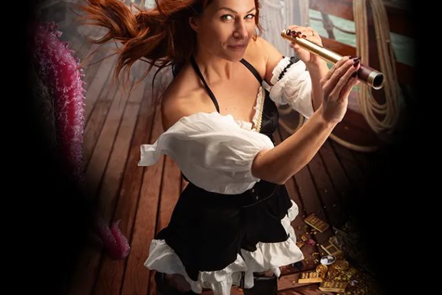 Femme en tenue de pirate regardant dans une longue-vue sur le pont d'un navire, salle Le trésor englouti, Under Escape