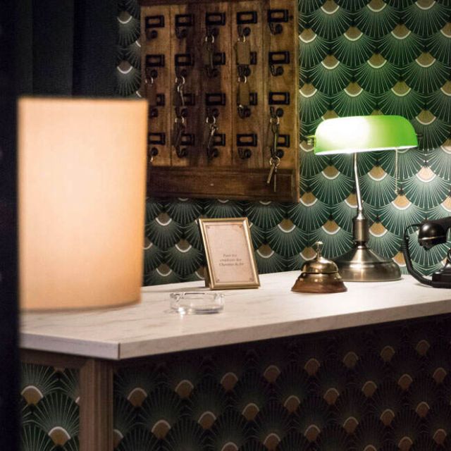 Réception d'hôtel avec lampe, téléphone ancien et casiers sombres, salle Sunhill Hotel chez Escape Time à Saint-Herblain
