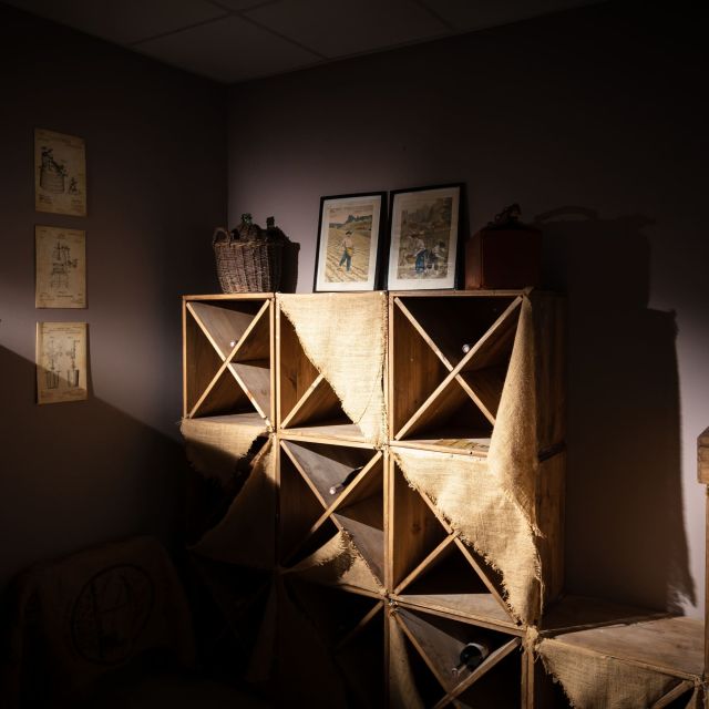 Pièce sombre aux caisses en bois, gravures murales et mobilier ancien du Château de Luc