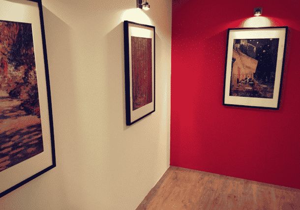 Couloir du musée avec murs rouge vif et beige, cadres d'art encadrés, parquet clair