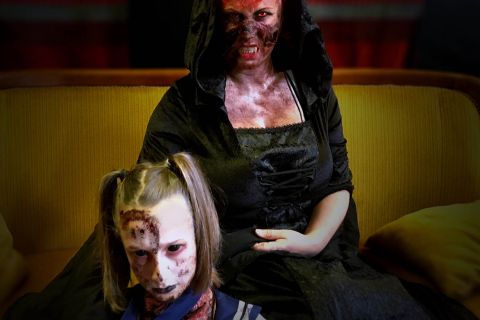 Deux figurantes maquillées en zombies sur un canapé jaune, décor horrifique de l'Hôtel transylv'ales