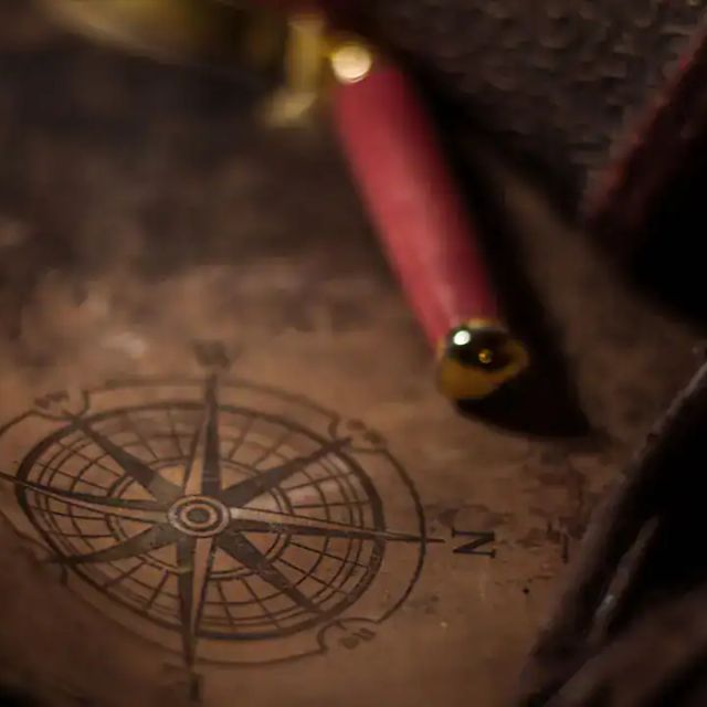 Rose des vents gravée sur du cuir et plume rouge, salle Le Repaire de Rackham