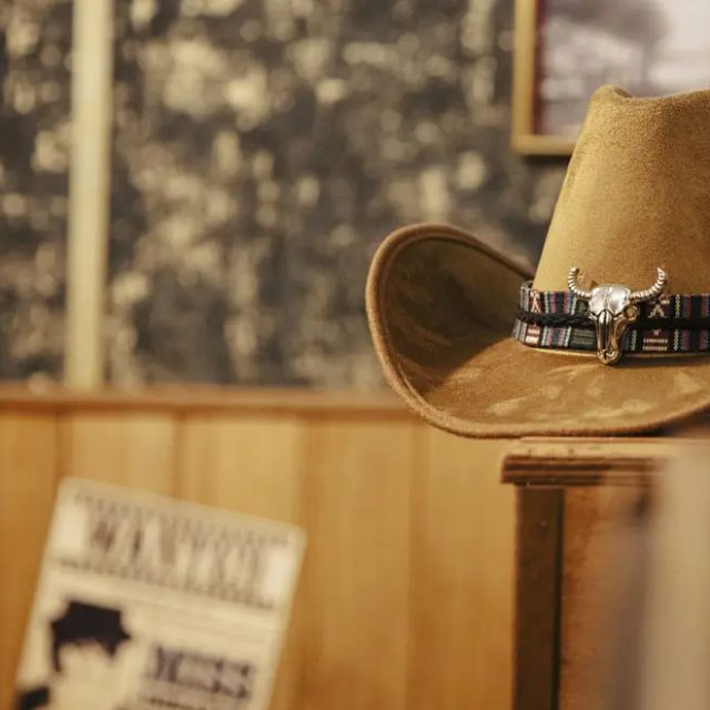 Chapeau de cow-boy sur un piédestal devant un mur à motifs et un avis Wanted, salle Le Silver Express à Pertuis