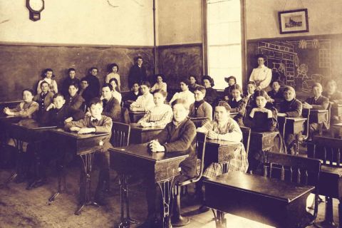 Ancienne photo de classe en teintes sépia, élèves assis à leurs pupitres, salle Disparitions chez Unlocked Laval