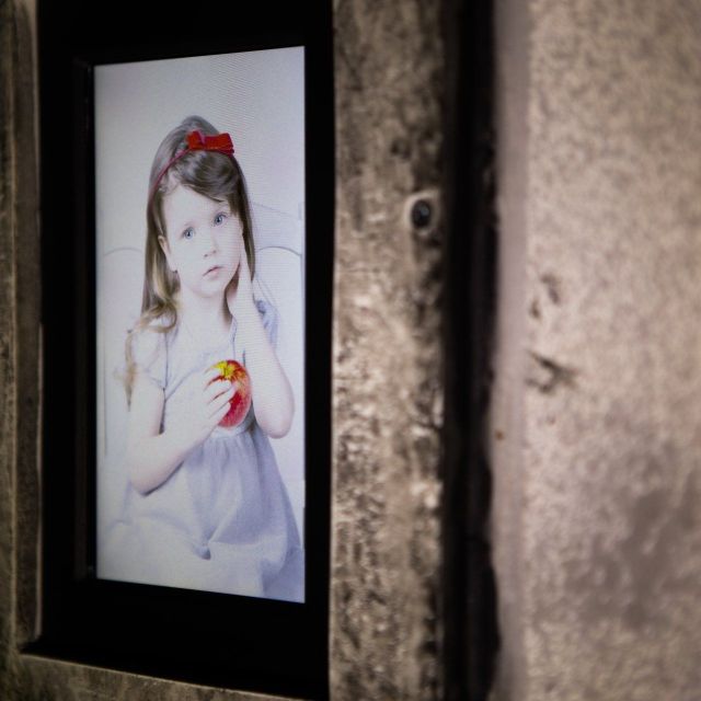 Portrait encadré d'une fillette au nœud rouge sur un mur de béton, décor Rashomon Escape