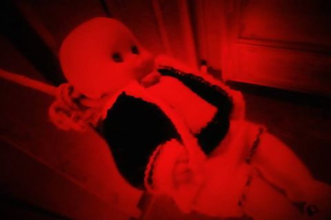 Mannequin recouvert de tissu rouge vif dans une ambiance rouge sombre, chez Issue Secrète