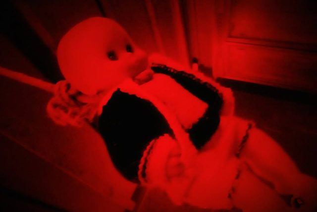 Mannequin recouvert de tissu rouge vif dans une ambiance rouge sombre, chez Issue Secrète