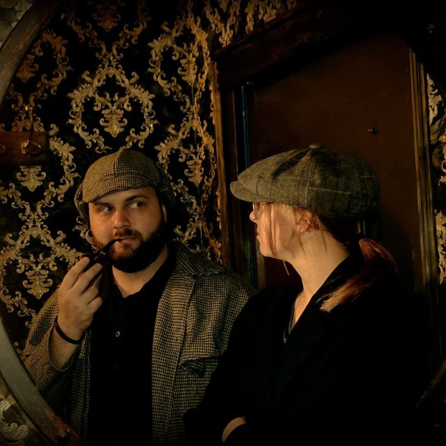 Deux hommes en casquette dans l'embrasure ronde d'une porte de coffre, salle Sherlock Holmes chez Freeing à Saint-Maximin