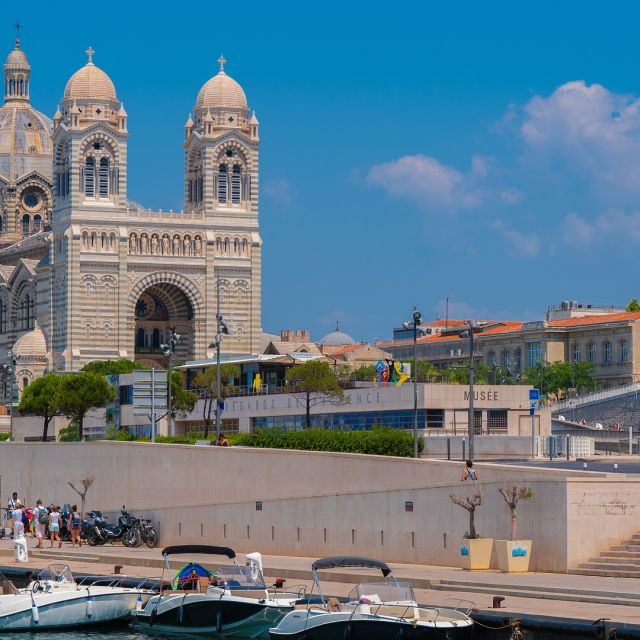 Cathédrale à coupoles au bord de l'eau avec bateaux amarrés, enseigne Hunting Town à Marseille