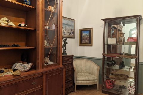 Salon aux boiseries claires avec vitrine de collection et fauteuil, salle Le musée chez GG escape game à Paris