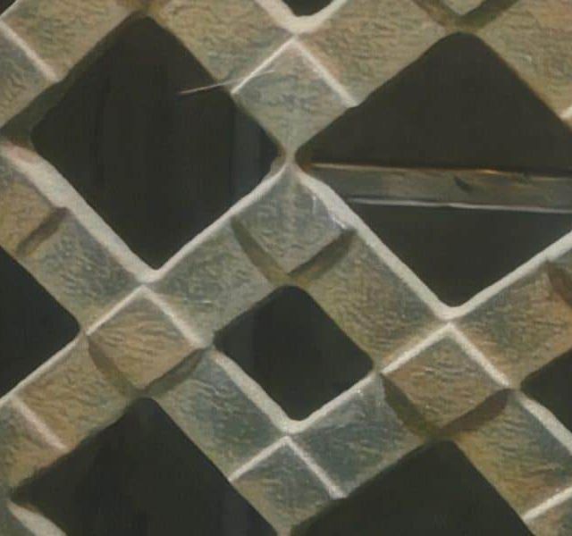 Motif de losanges entrecroisés en pierre sur un panneau de porte, visuel de Mission Exit à Montpellier