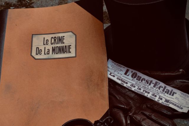 Dossier d'enquête Le Crime de la Monnaie posé près d'une coupure du journal L'Ouest-Éclair