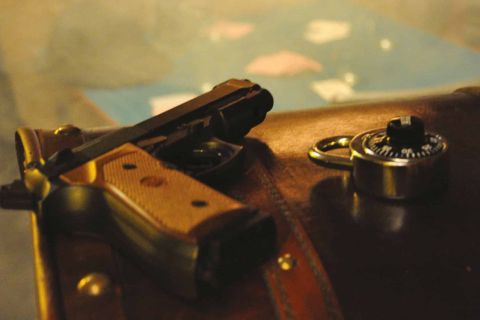 Pistolet à crosse de bois près d'un cadenas à code sur du cuir, salle Le tripot de la courtoisie chez Nant'escape