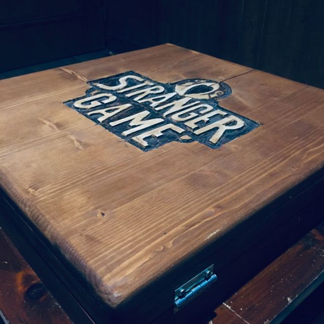 Table en bois portant le logo Stranger Game, jeu de Kubik, escape game à Paris