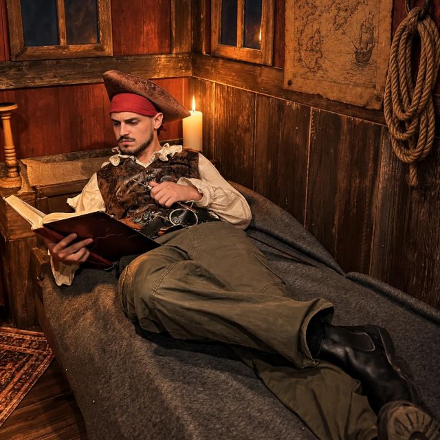 Pirate en tricorne lit un document dans une cabine en bois, ambiance Le Mystère du Bad Fortune