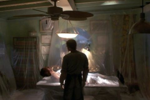 Homme de dos devant une table de laboratoire sous un ventilateur de plafond, salle Sur les traces de Dexter, Arles