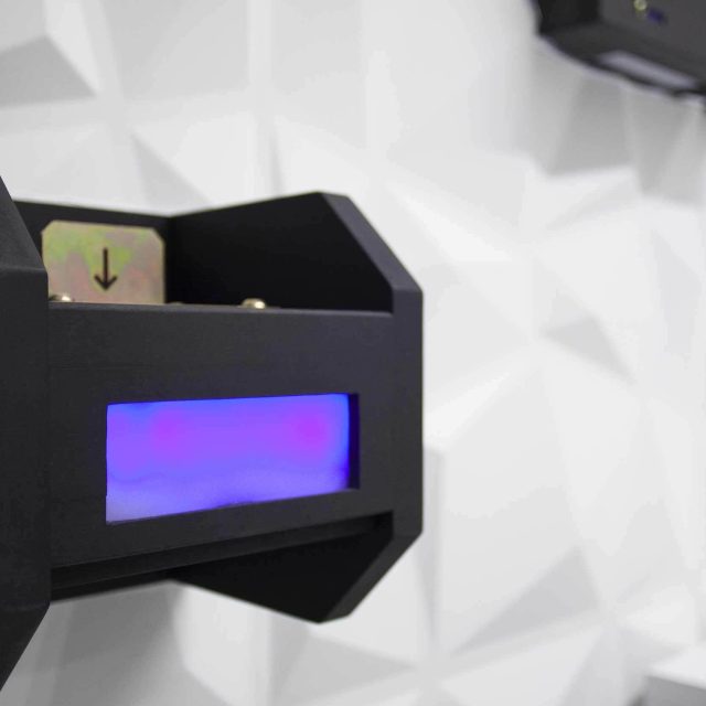 Boîtier noir avec écran bleu lumineux et symbole directionnel, chez LIVE Corp. Escape Game à Montpellier