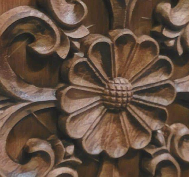 Rosace de bois sculptée à pétales sur un panneau brun, décor de la salle Le butin chez Mission Exit à Montpellier