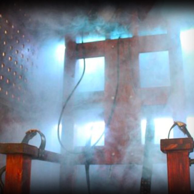 Fenêtres éclairées de bleu dans la brume, sièges rouges au premier plan, salle Le cirque hanté chez Freeing à Saint-Maximin