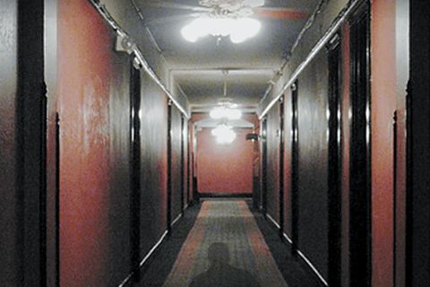 Couloir d'hôtel aux murs rouges et ombre au sol, salle Seven à Crolles