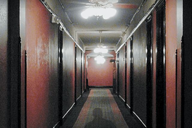 Couloir d'hôtel aux murs rouges et ombre au sol, salle Seven à Crolles