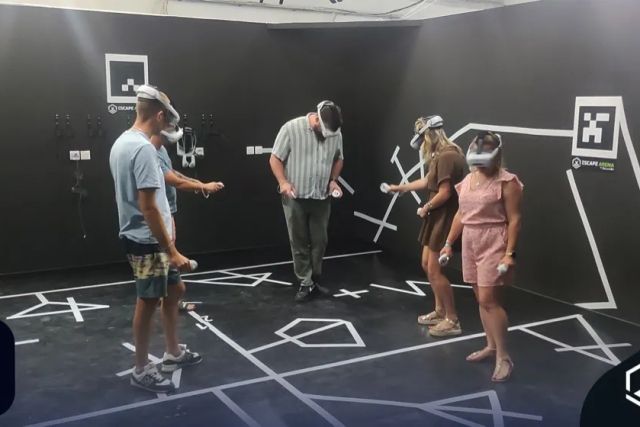 Cinq joueurs en réalité virtuelle dans une salle sombre aux murs noirs chez BassinVR