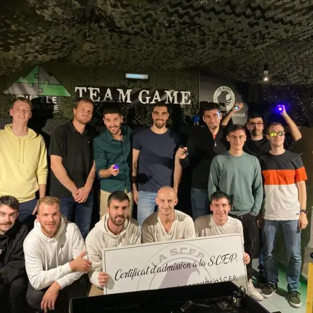 Équipe d'une vingtaine de joueurs posant dans une cave voûtée avec un certificat, salle SCEP Unité Spéciale à Grenoble