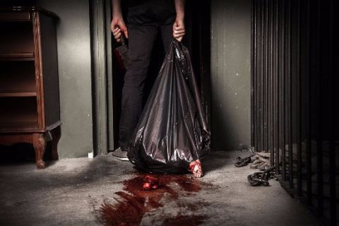 Personne tenant un sac poubelle noir au-dessus d'une tache rouge dans Bienvenue en enfer