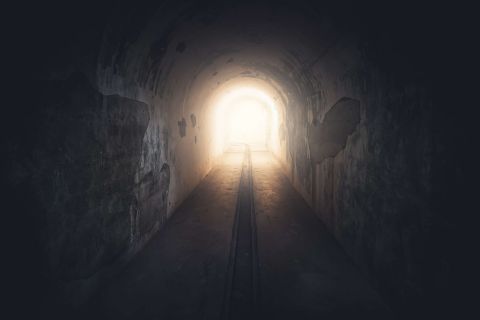 Long tunnel sombre menant à une lumière vive, visuel de La Synapserie à Riom