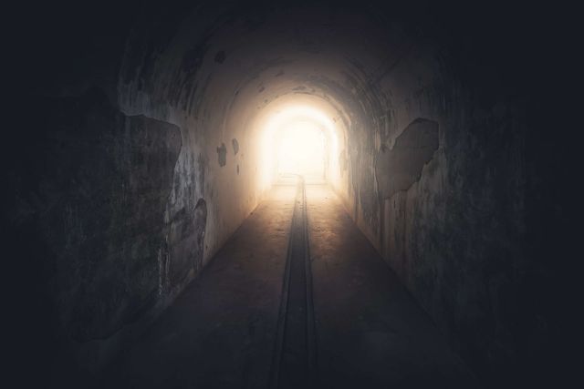 Long tunnel sombre menant à une lumière vive, visuel de La Synapserie à Riom