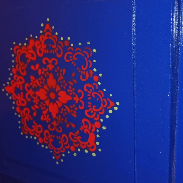 Mandala rouge en dentelle sur une porte bleu vif, salle La mystérieuse roulotte à La Roche-sur-Yon