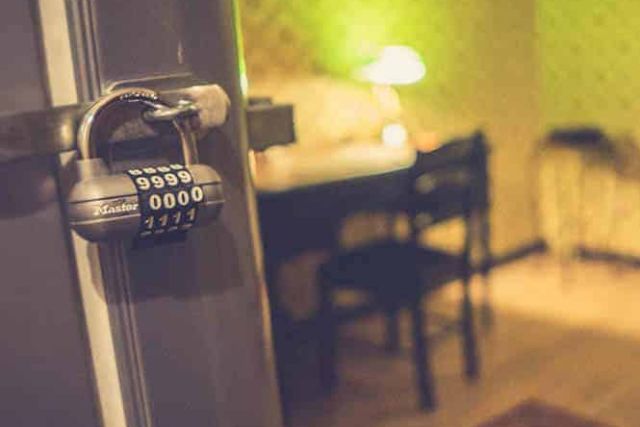 Cadenas à combinaison sur un montant de porte devant un bureau éclairé de jaune, salle L'appartement du Dr Kang, Paris