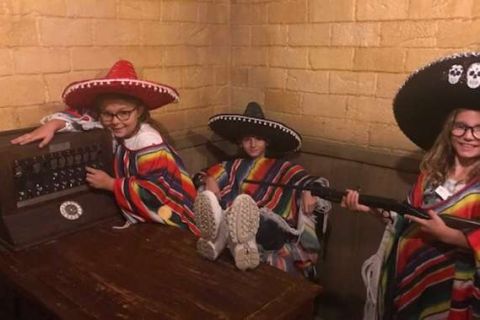 Trois enfants en costumes mexicains dans une cellule de prison, posant avec des accessoires