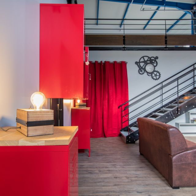 Salon d'accueil avec fauteuil en cuir, bureau rouge et mezzanine à escalier métallique, Spirit Game à Douvaine