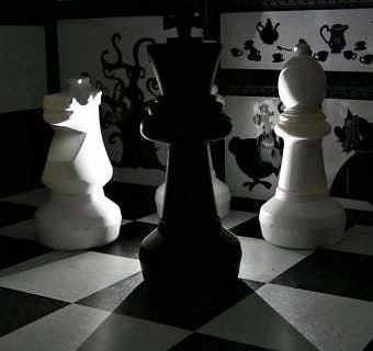 Pièce aux tons contrastés avec pièces d'échecs géantes et silhouettes noires