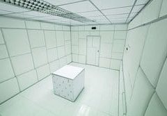 Pièce blanche aux murs carrelés avec cube blanc au centre, chez Labyrintoom à Berlin