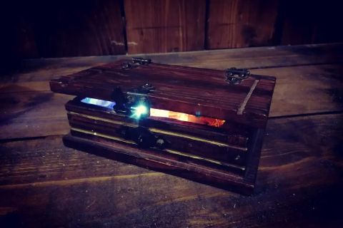 Coffret de bois posé sur un plancher et entrouvert sur une lueur bleue et rouge, salle L'héritage de tante Suzanne, Zone 72