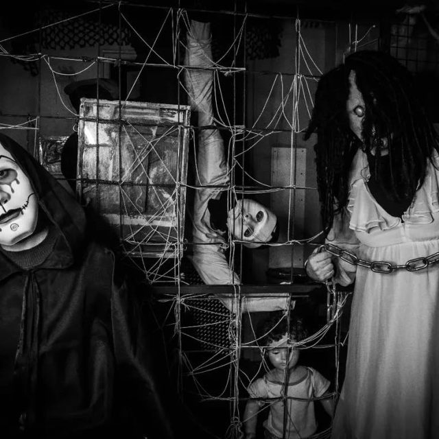 Personnage au masque blanc et femme en chemise de nuit dans une pièce couverte de filets, salle Esprit es-tu là