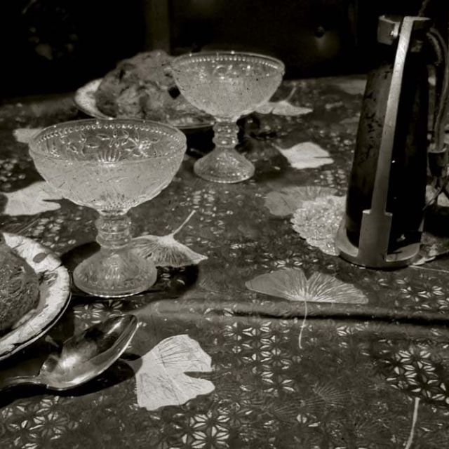 Table dressée avec coupes et assiettes poussiéreuses, noir et blanc, salle Le manoir des sœurs Aubépine à Angers