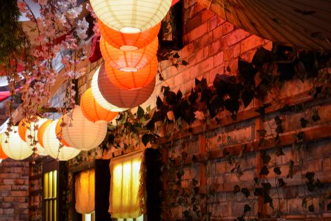 Lanternes rouges illuminées, décor asiatique, murs de brique, végétation suspendue dans Mission Tokyo