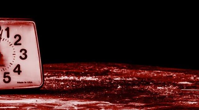 Réveil ancien posé sur une surface rouge sombre, visuel d'Intrappola