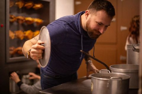 Homme soulevant un couvercle de casserole dans une cuisine aux broches de poulets, salle Panique en cuisine chez Gaillard Académie