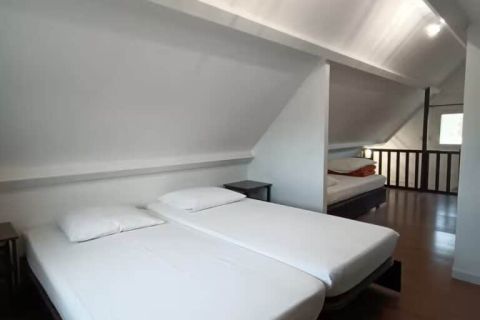 Chambre blanche sous les combles avec deux lits simples, visuel des salles de Clécy Évasion à Clécy