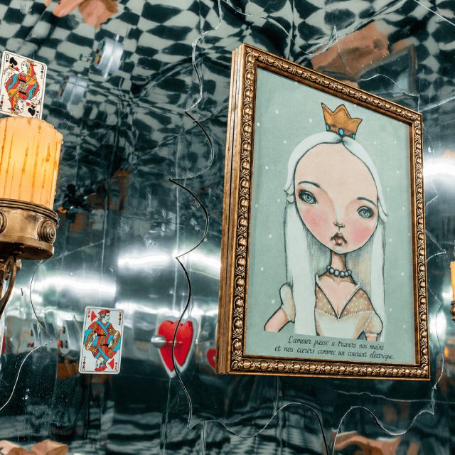 Pièce aux murs en damier et miroirs avec portrait de reine blonde et cartes à jouer, enseigne Délivrés à Pau