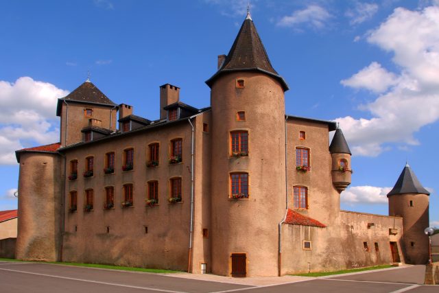 Château de brique rose à tours coniques sous un ciel bleu, salle Le dernier secret au Château de Luttange